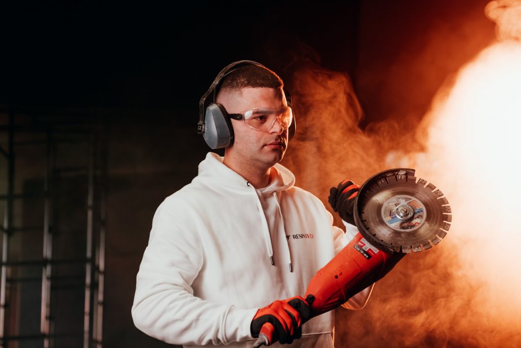 Mitarbeiter von Resintech arbeitet mit dem Winkelschleifer an Beton